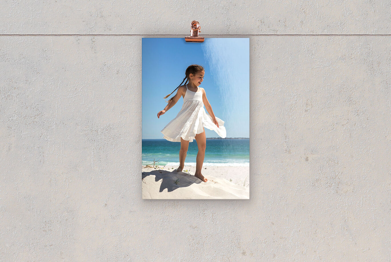 A child in a white dress plays on the beach and enjoys the sunbeam.