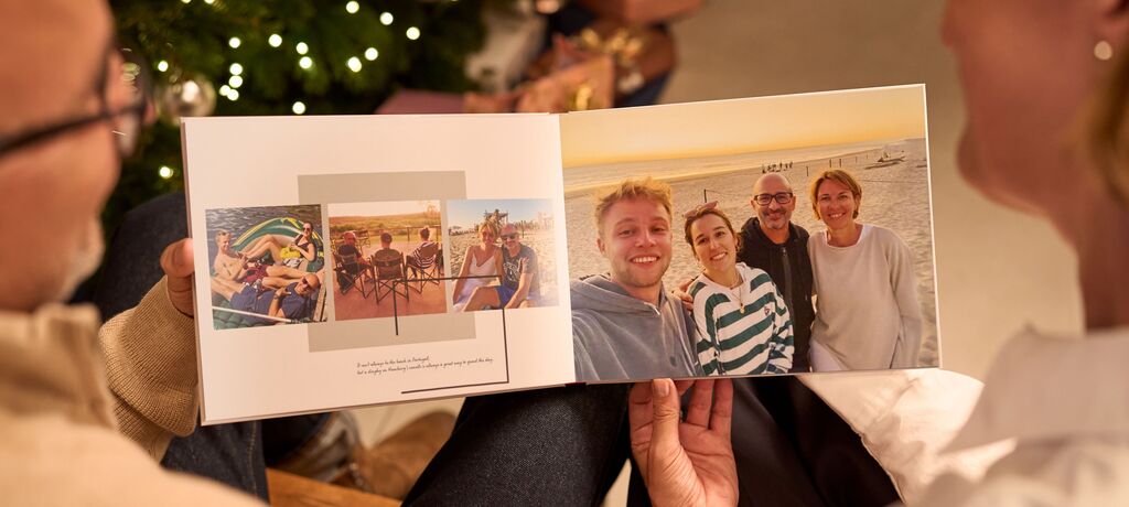 A couple flipping through a CEWE PHOTO BOOK with vacation photos, showing happy moments