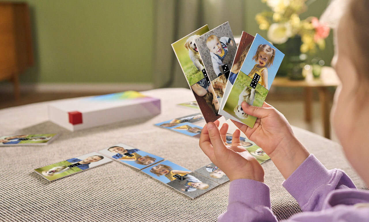 A child lovingly holds cards with family photos and colorful motifs in their hands.