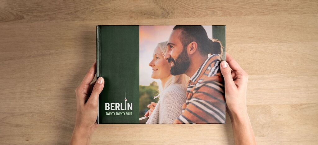 A person holds a CEWE photo book with a cozy design.