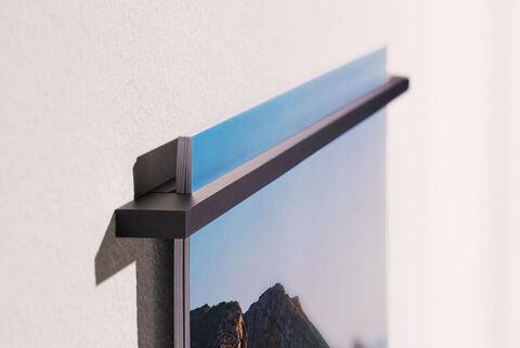 Wall picture featuring a mountain landscape, cut off at the top, in a modern display.