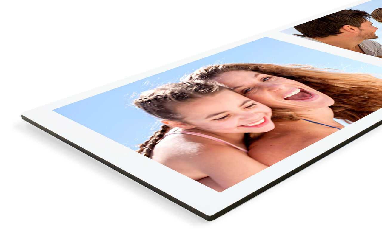 Two happy women posing in the sun with a CEWE photo book. They smile lovingly at the camera, showing joy in the moment.