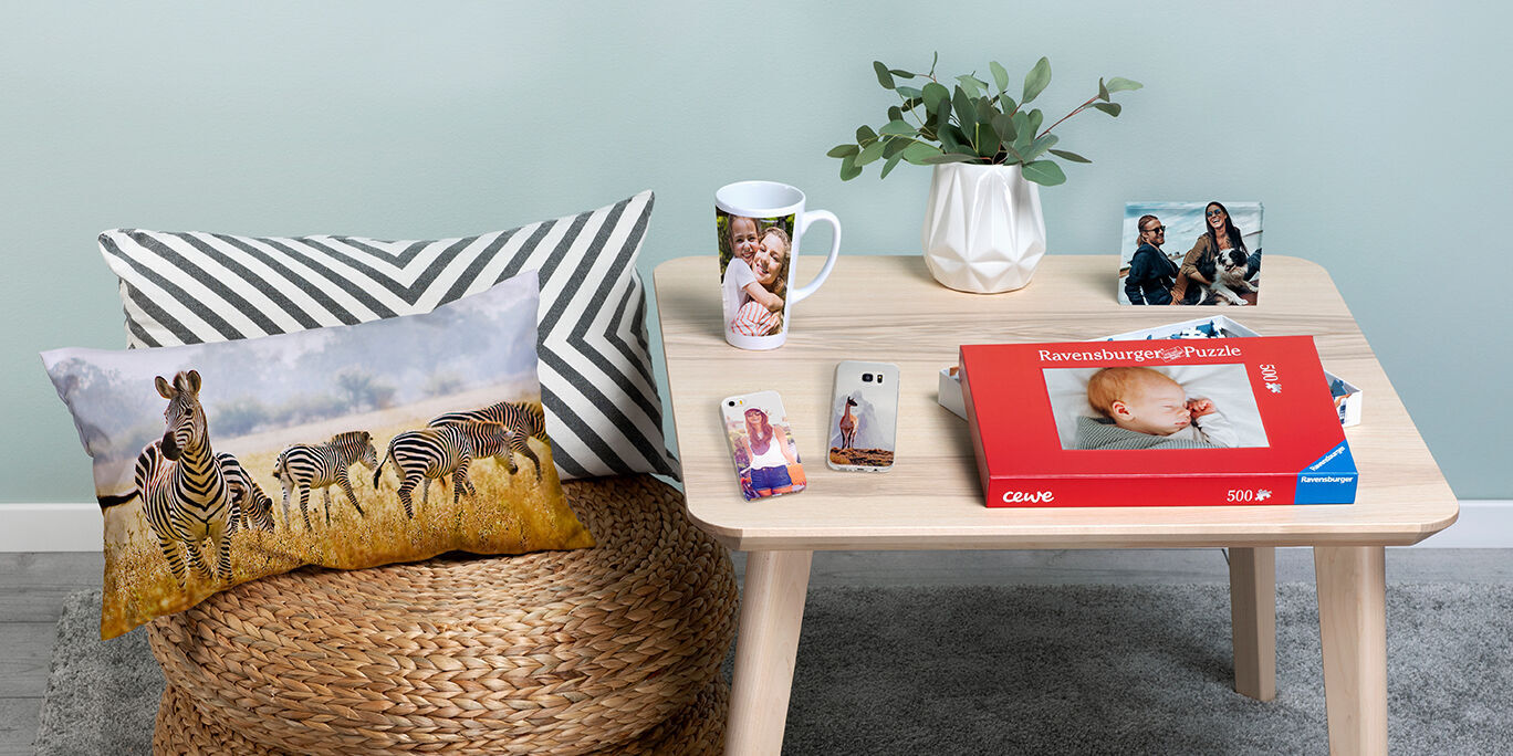 Zebras stand in the wild in front of a cozy table with photo gifts of CEWE products.