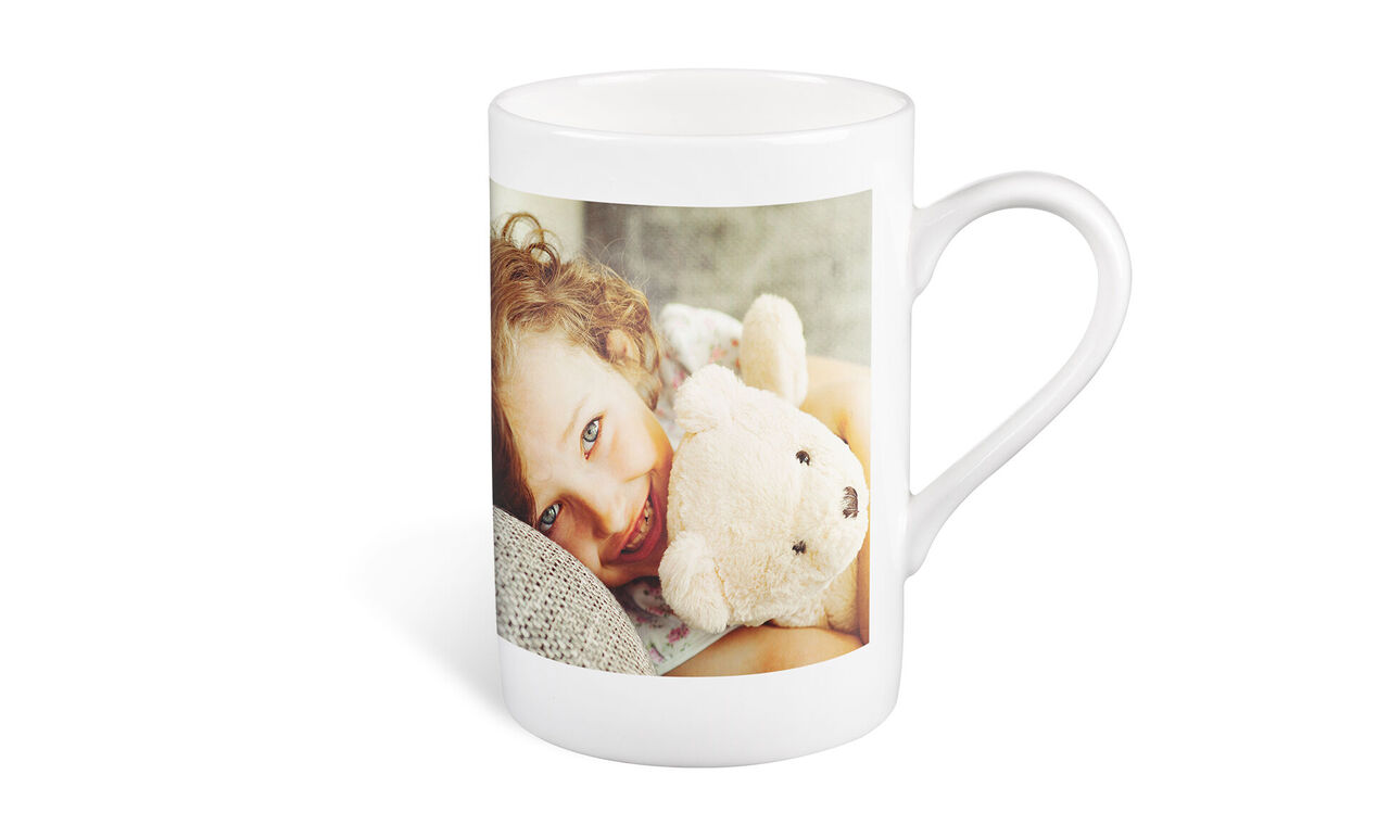 A mug with a photo and a plush bear.