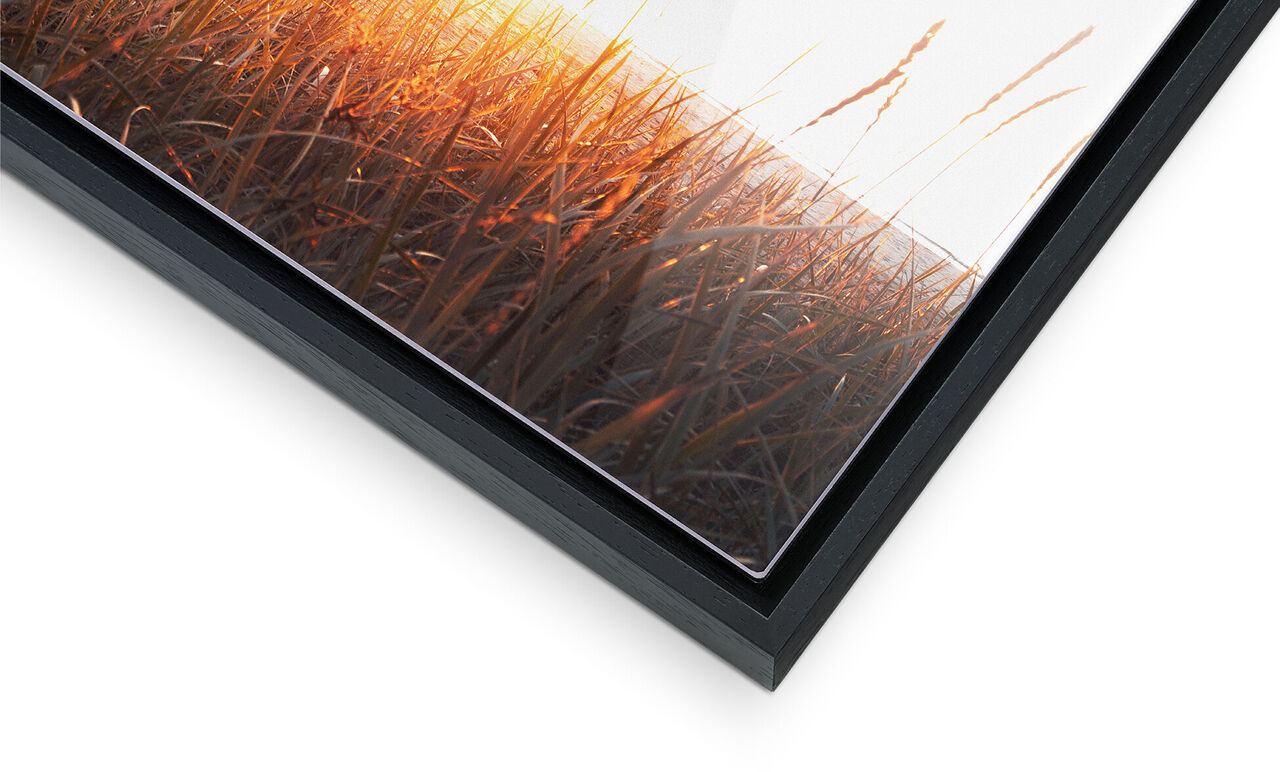 Close-up of a frame with a colorful picture of a sunset over grass.