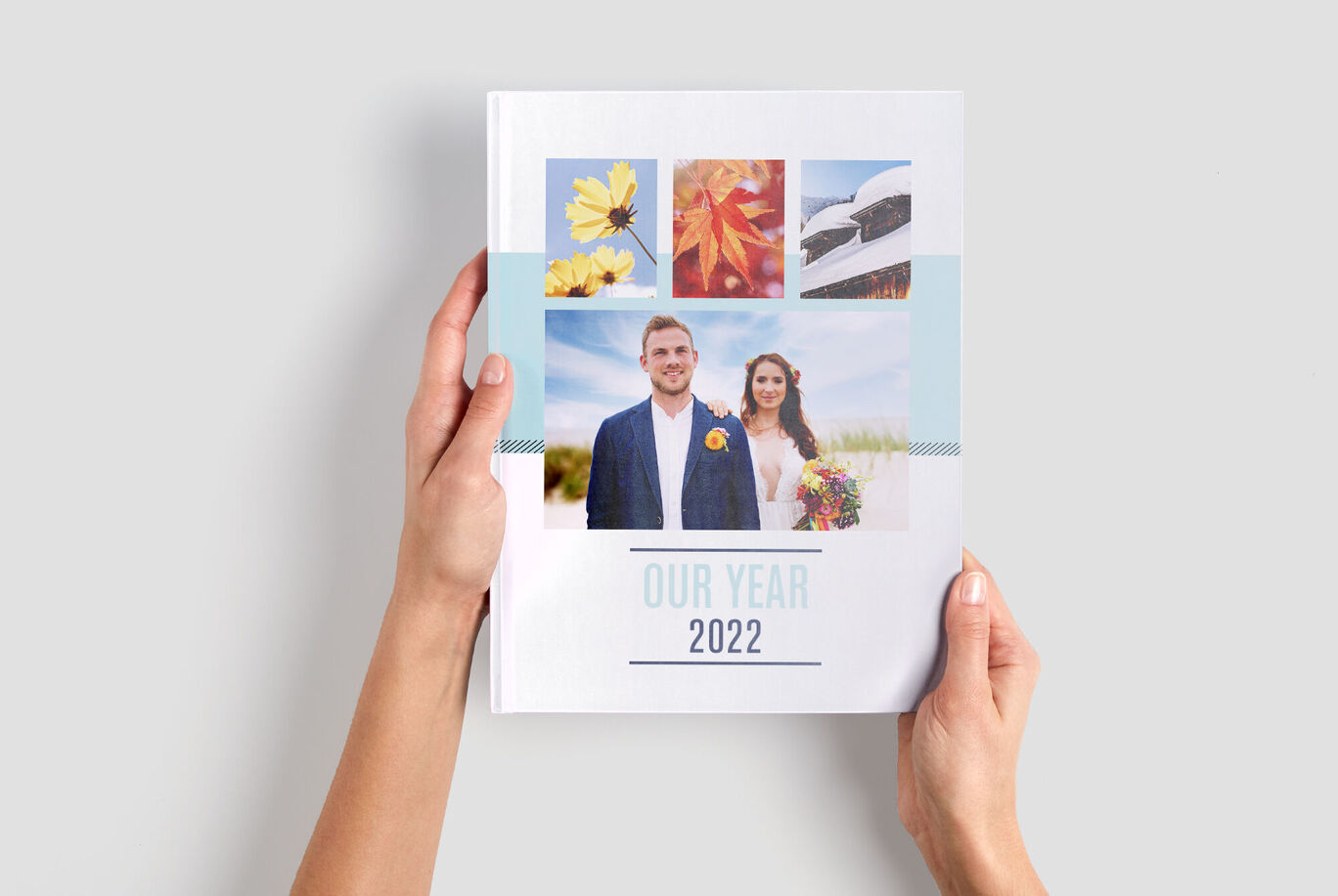 A person holds a CEWE photo book with colorful images showing the memories of 2022