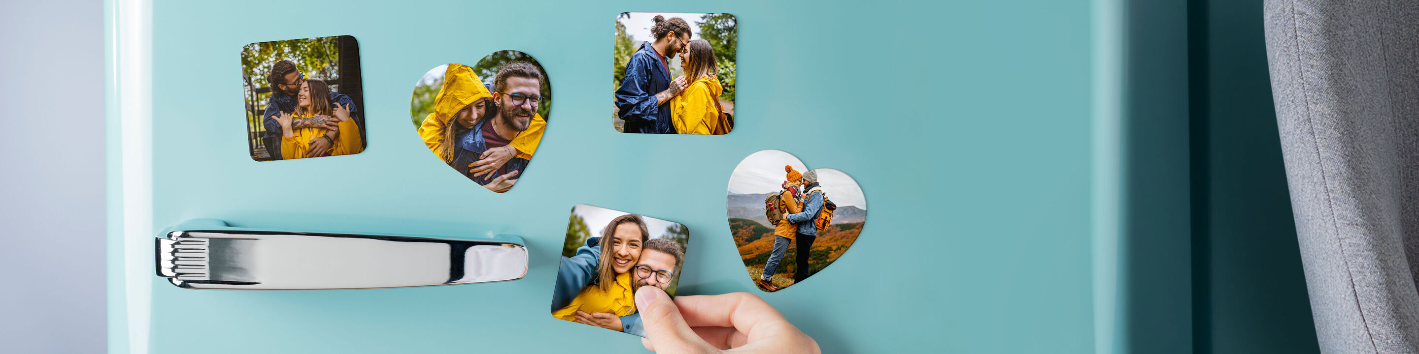 Person attaching heart-shaped photo magnets to a blue fridge door with their favorite images.