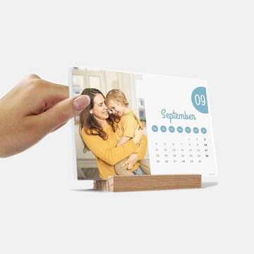 Hand holding a small photo calendar with an image and the month of September