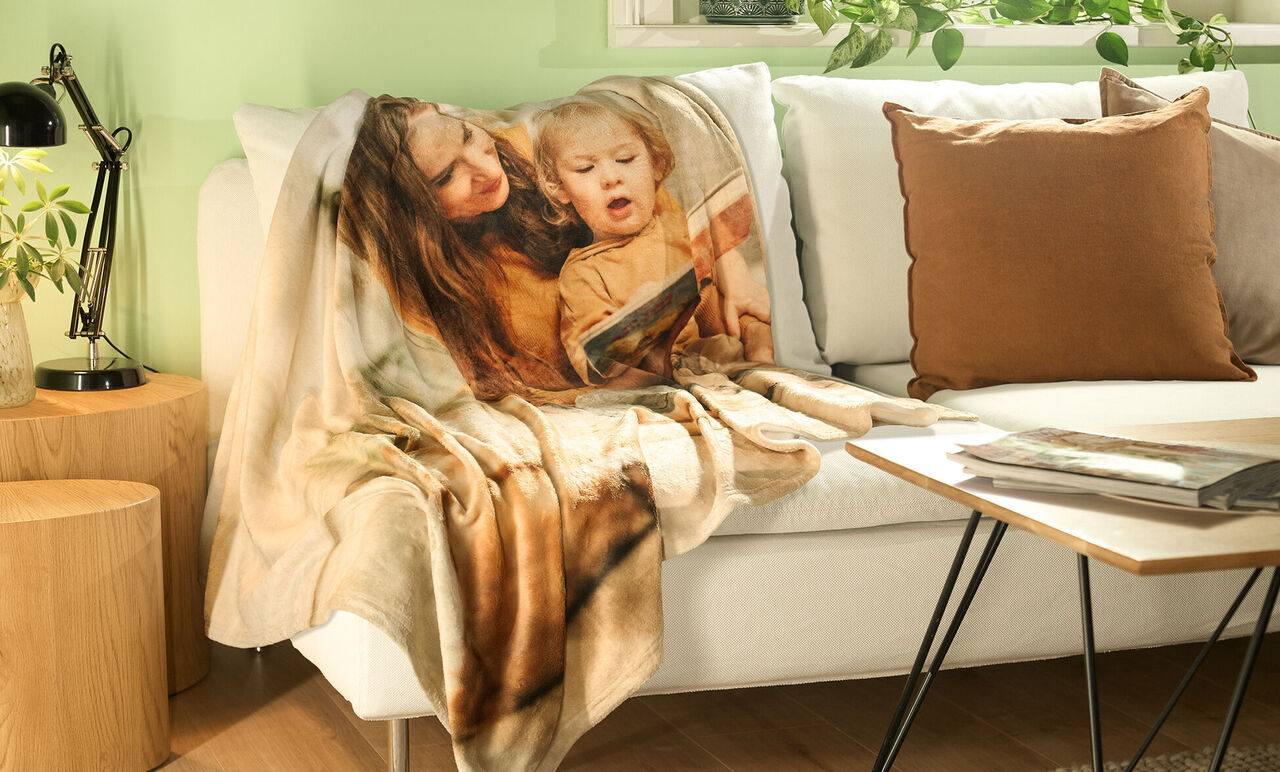 Beautiful blanket on a cozy sofa, surrounded by plants and a pillow