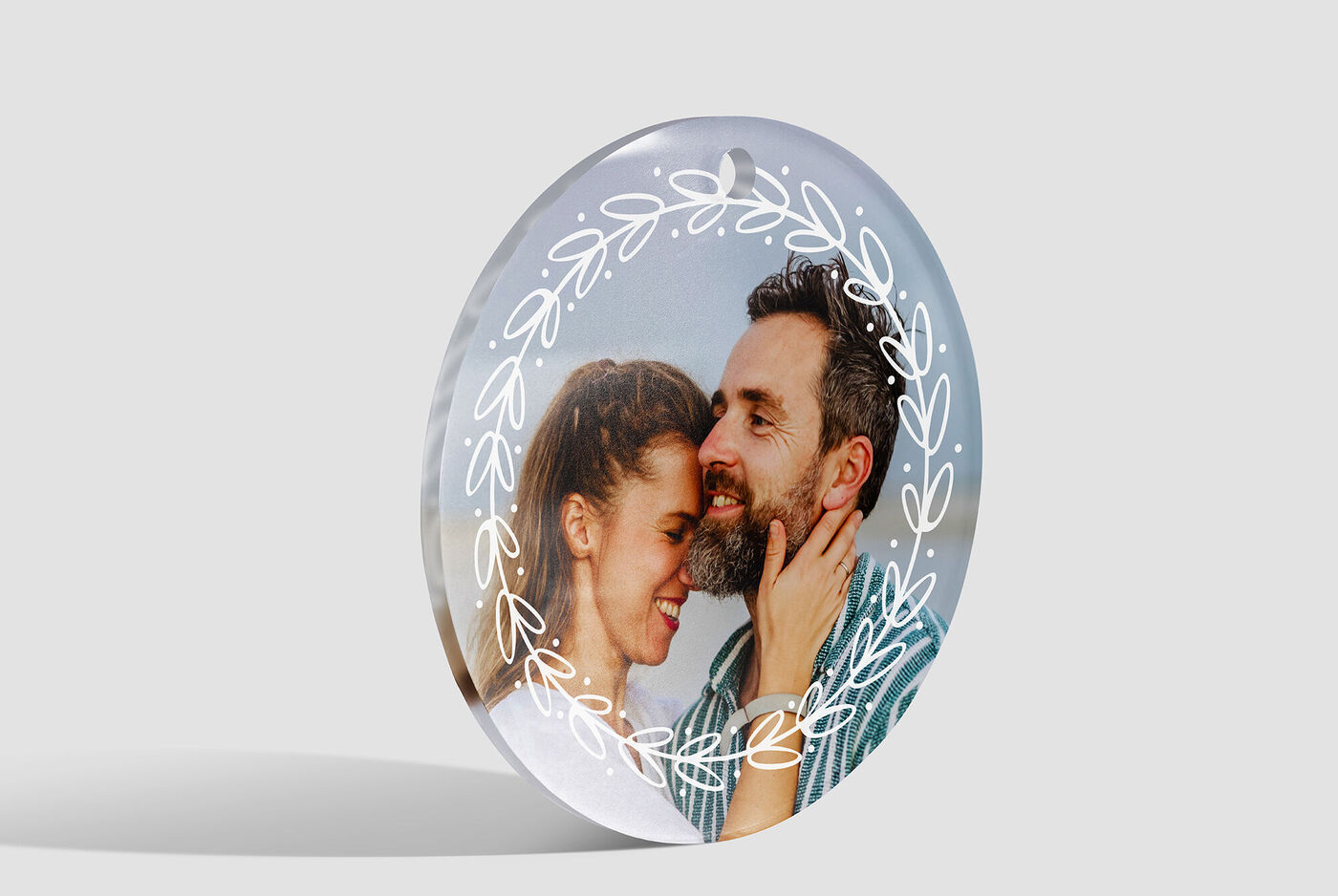 A round, transparent photo product with a loving couple and floral details in the background.