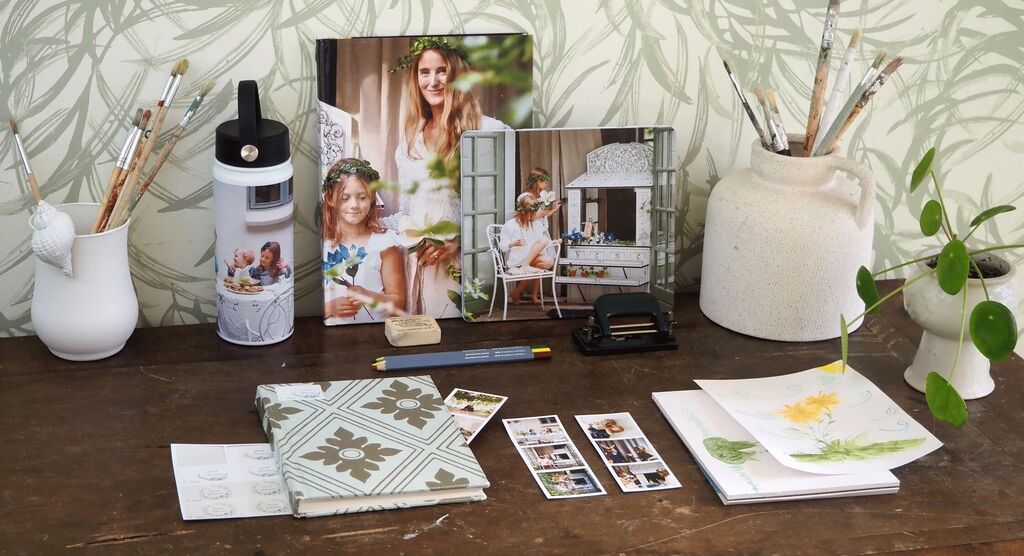 A lovingly designed creative workspace with a photo book, drawings, and plants.
