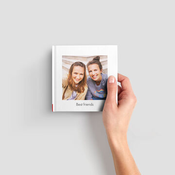 A hand holding a photo book titled 'Best Friends' with a window for a personal photo.
