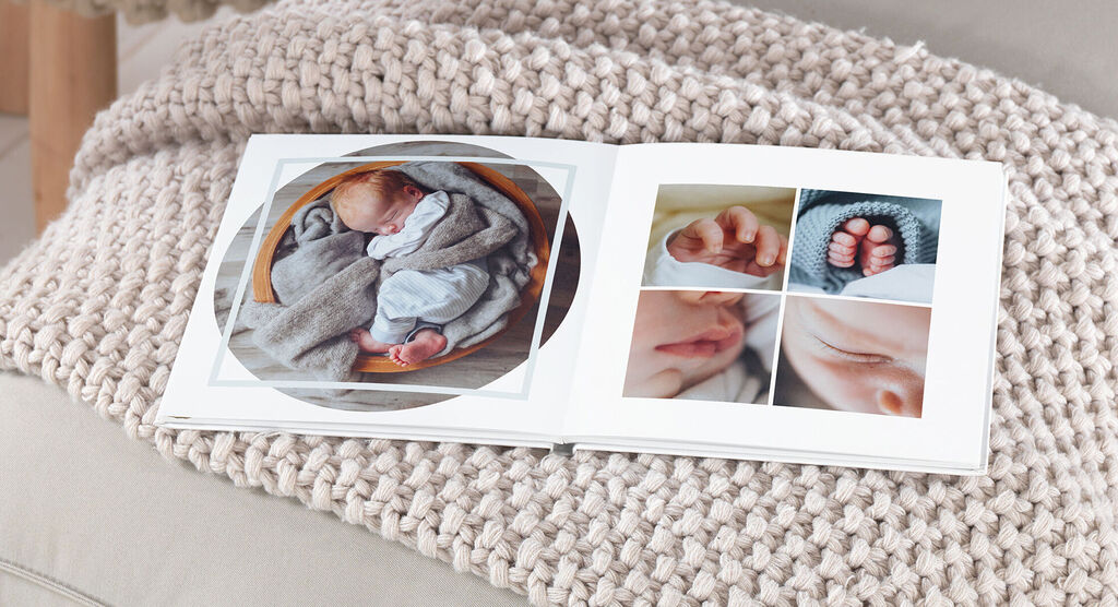 An open photo book displays loving baby photos in soft colors, featuring the baby's feet, face, and hands.