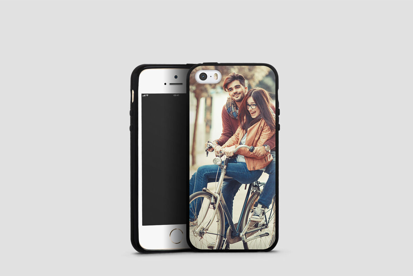A couple rides together on a bike, the person in front wears glasses and enjoys the ride.