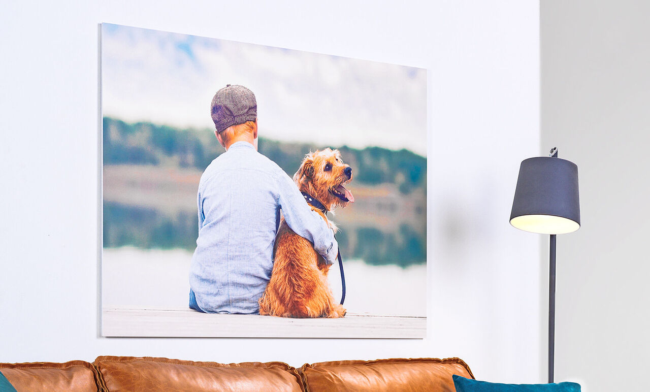 A boy with a blonde dog sits by the lake and enjoys the moment.