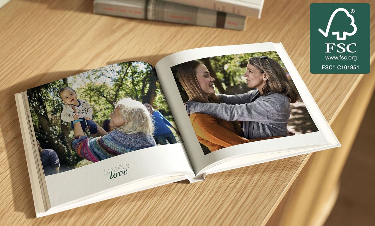 Open CEWE PHOTO BOOK on a table with pictures of family moments.