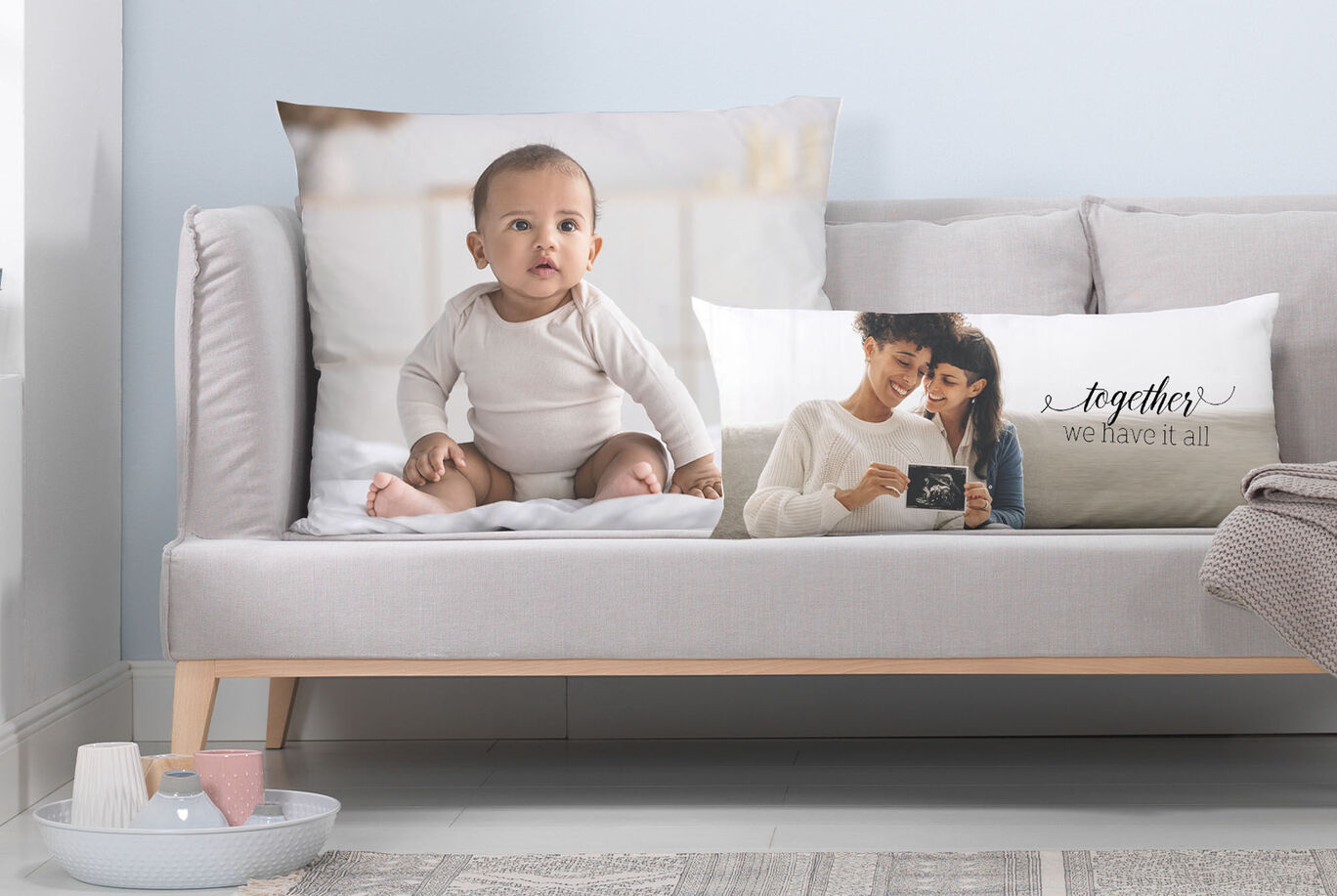 Two cushions on a sofa, one features a baby and the other shows a person with a heartfelt message