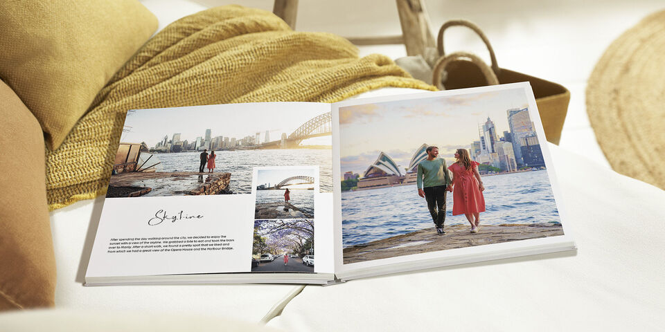 Open photo book on the beach with a couple happily walking.