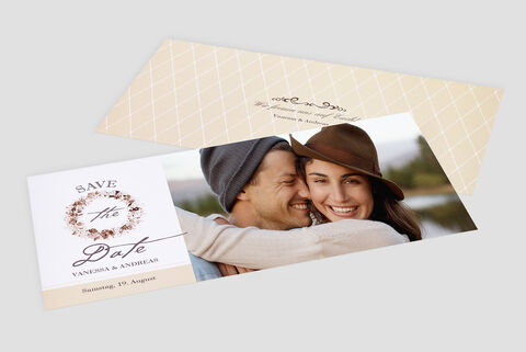 Couple lovingly embraces in nature with wedding invitation in the background