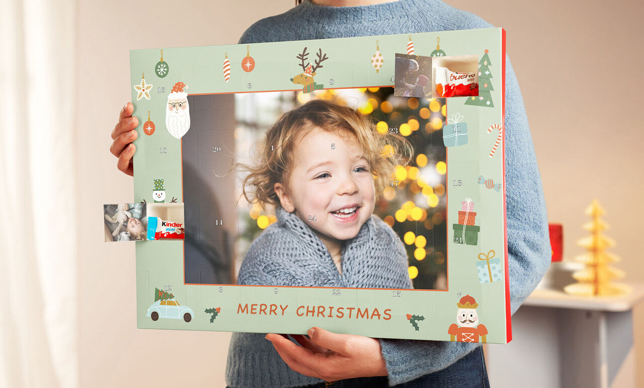A child holding a Christmas-themed picture frame in front of a festively decorated tree.