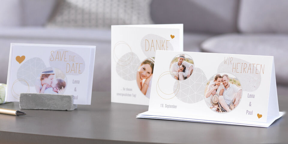 Three festive cards on a table: wedding invitation, thank you card, and save-the-date card.