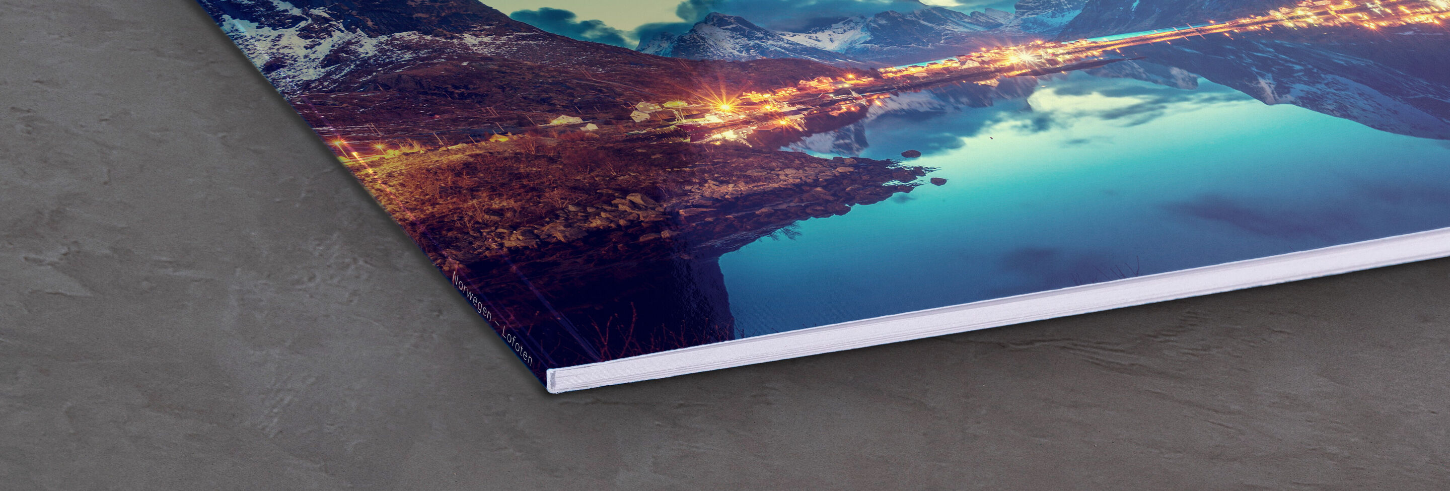 A corner of a CEWE photo book with a beautiful image of mountains and water reflecting shining light