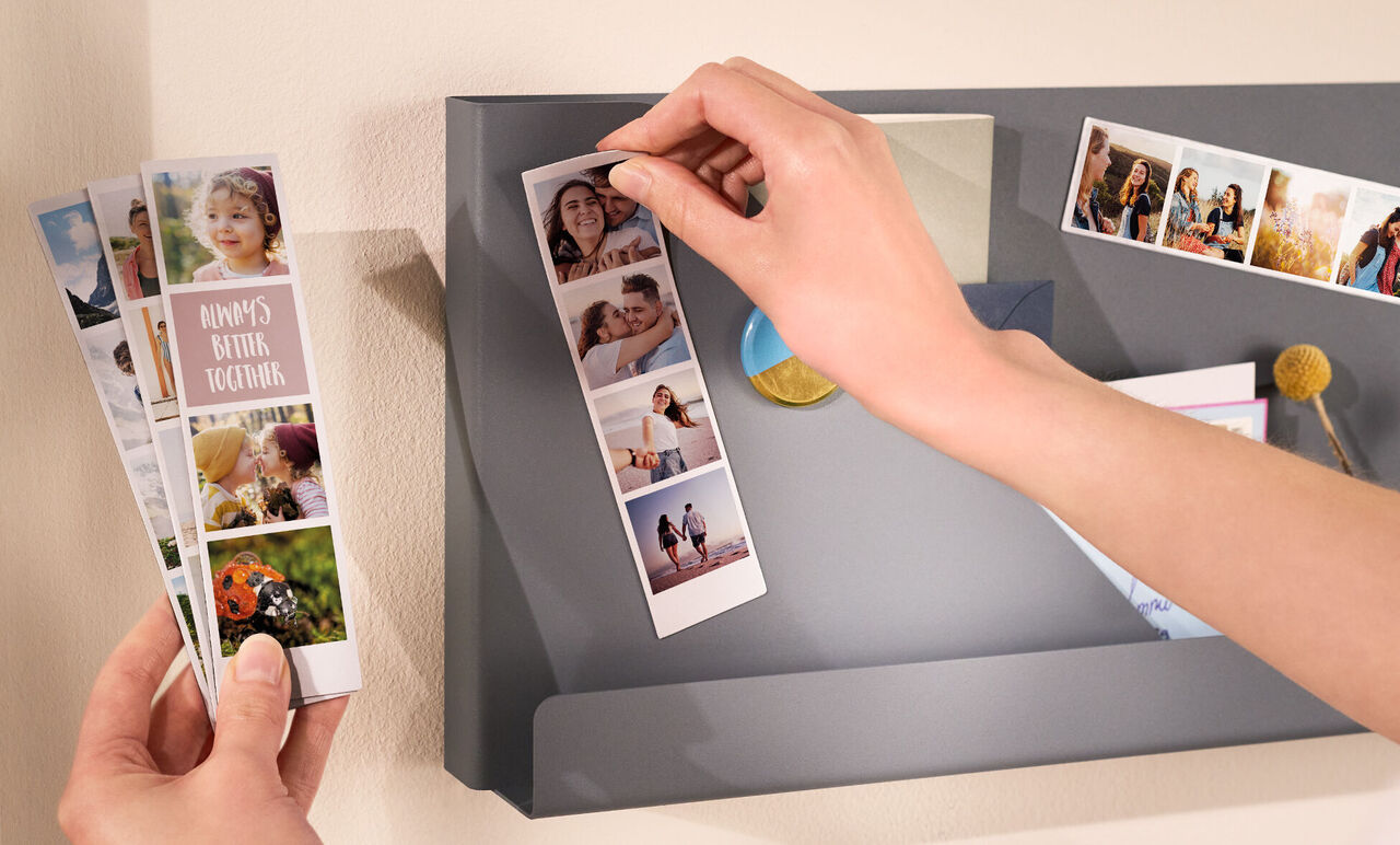 Someone is pulling a photo card from a gray wall pocket with more photo memories.
