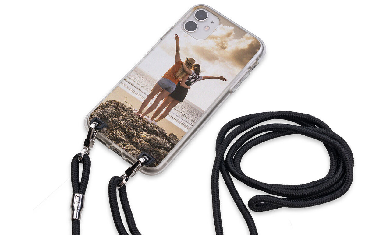 Two women standing on the beach giving a thumbs up. They are wearing their phone straps with a personalized smartphone case.