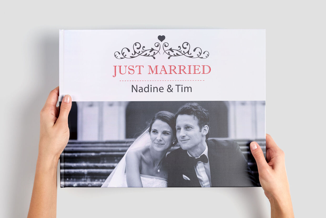Hands hold a CEWE PHOTO BOOK titled 'Just Married' with the names 'Nadine & Tim'