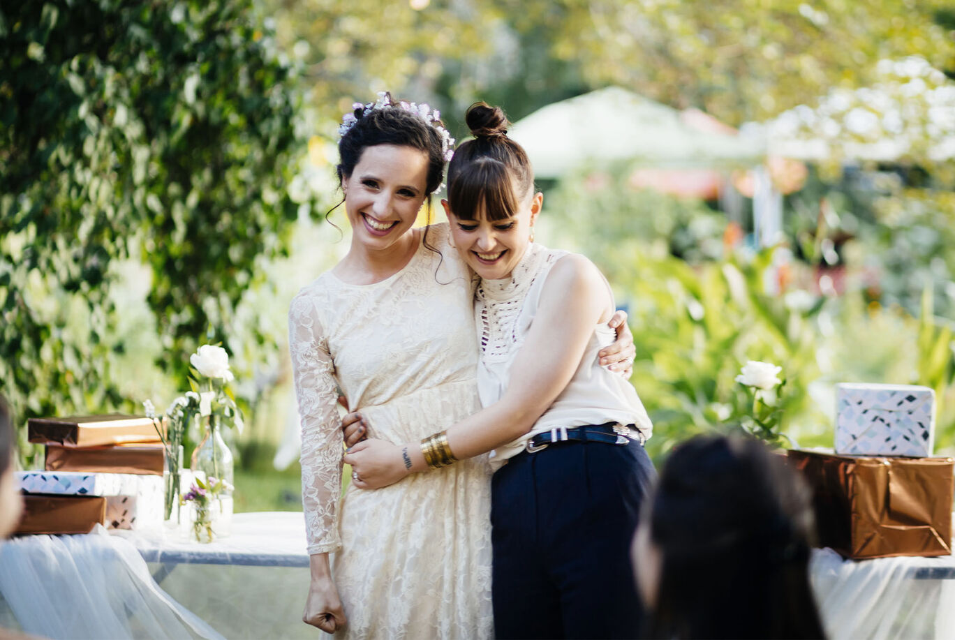 Two women warmly embrace at a festive outdoor location.