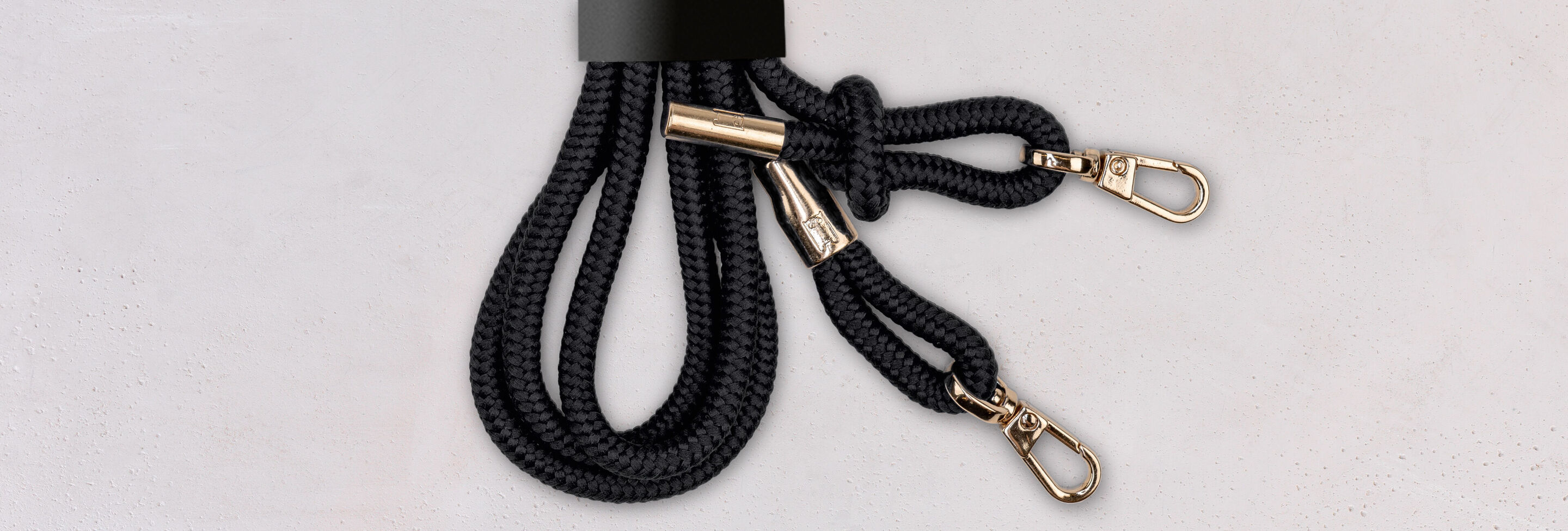 Black cord with two gold carabiners arranged elegantly
