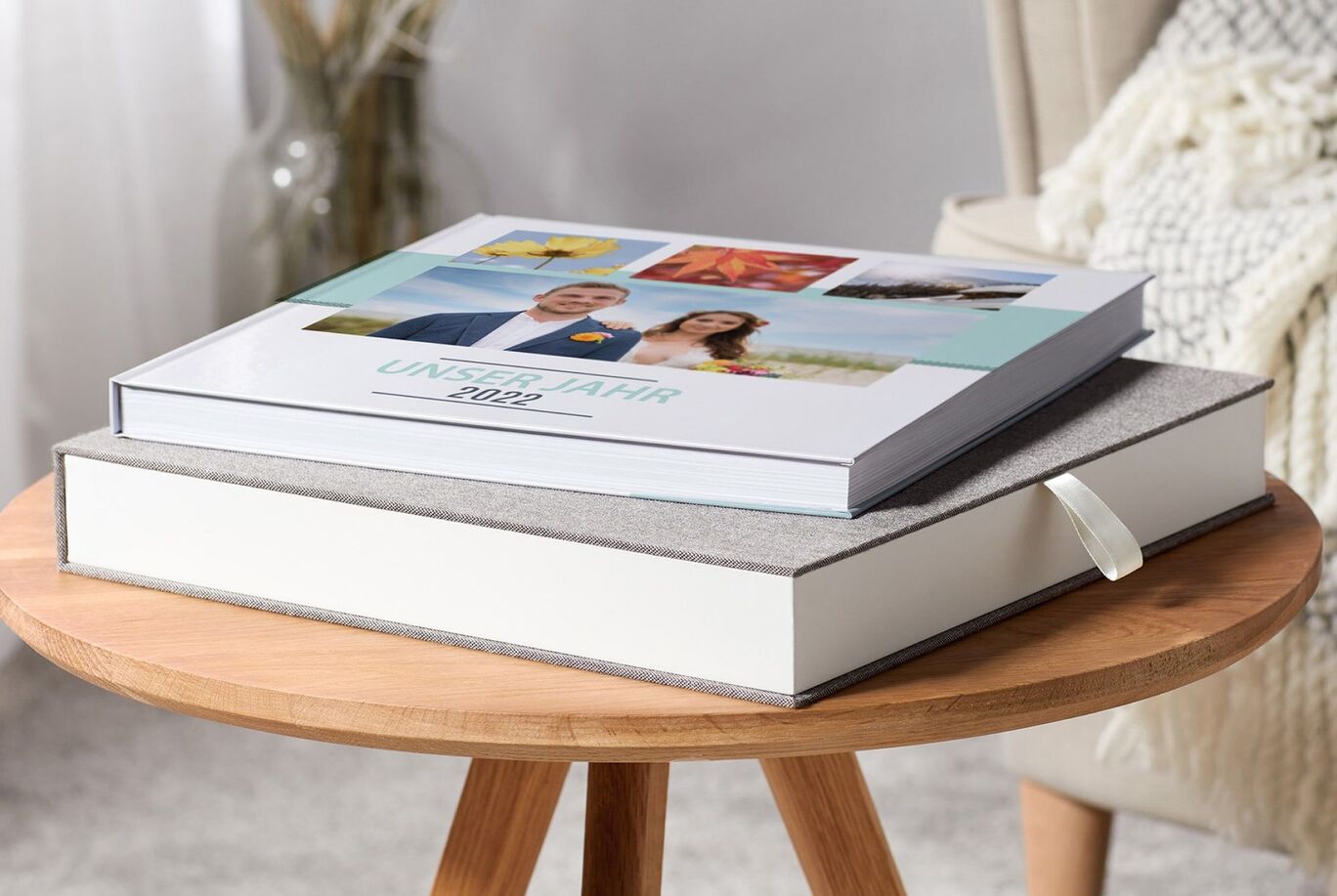 Two CEWE photo books on a wooden table, one is closed, the other is open.