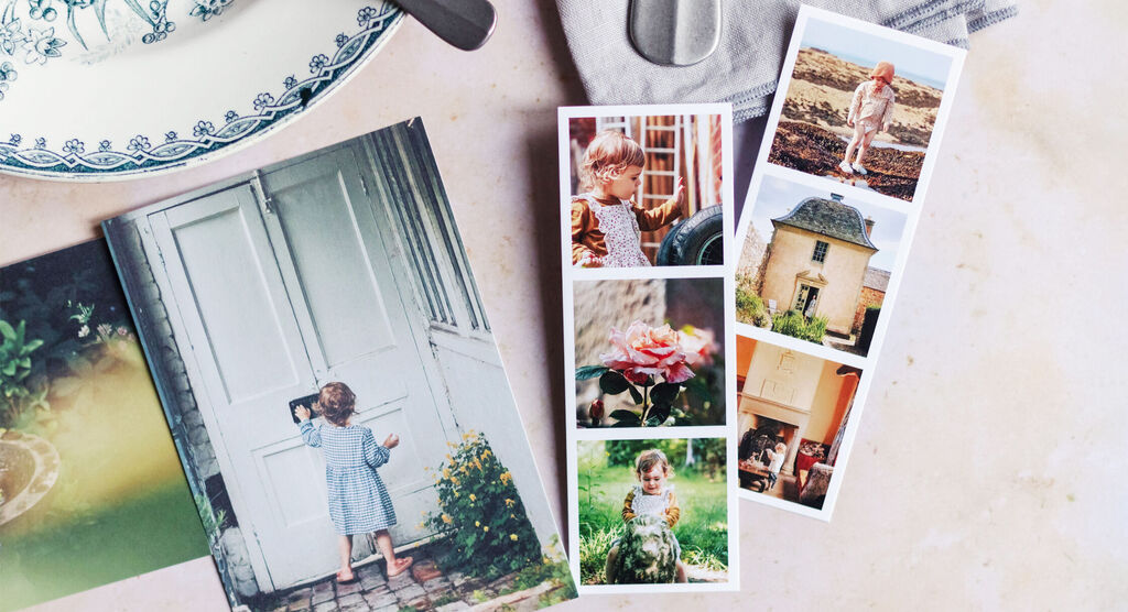 A blond little boy stands in front of a white door, looking in curiously. Next to him lies an open photo book with colorful images.