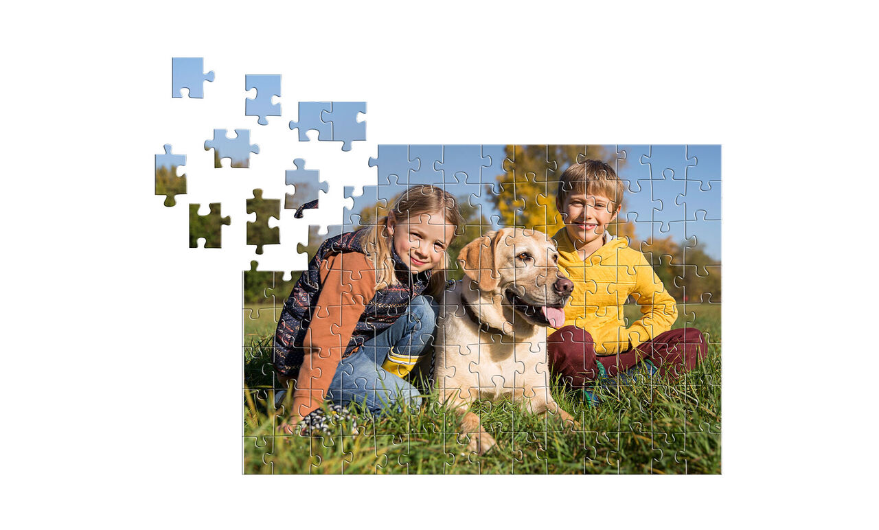Two children sitting in a garden with a dog, surrounded by puzzle pieces.