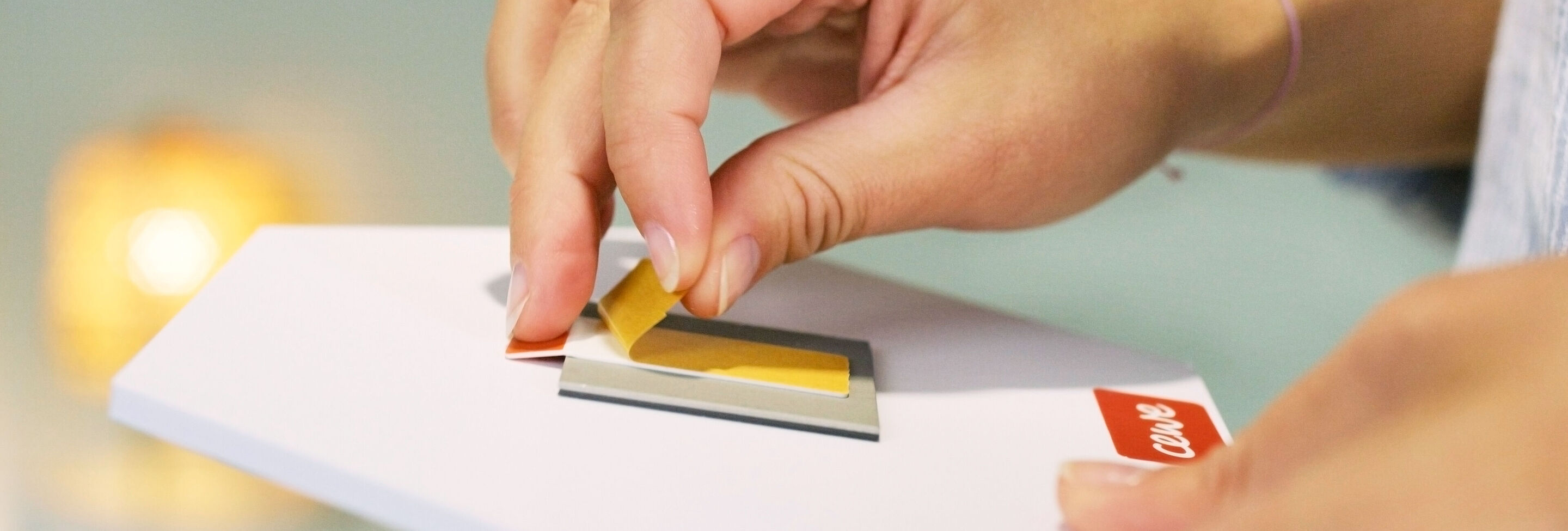 A hand peeling off a yellow film from a CEWE greeting card.