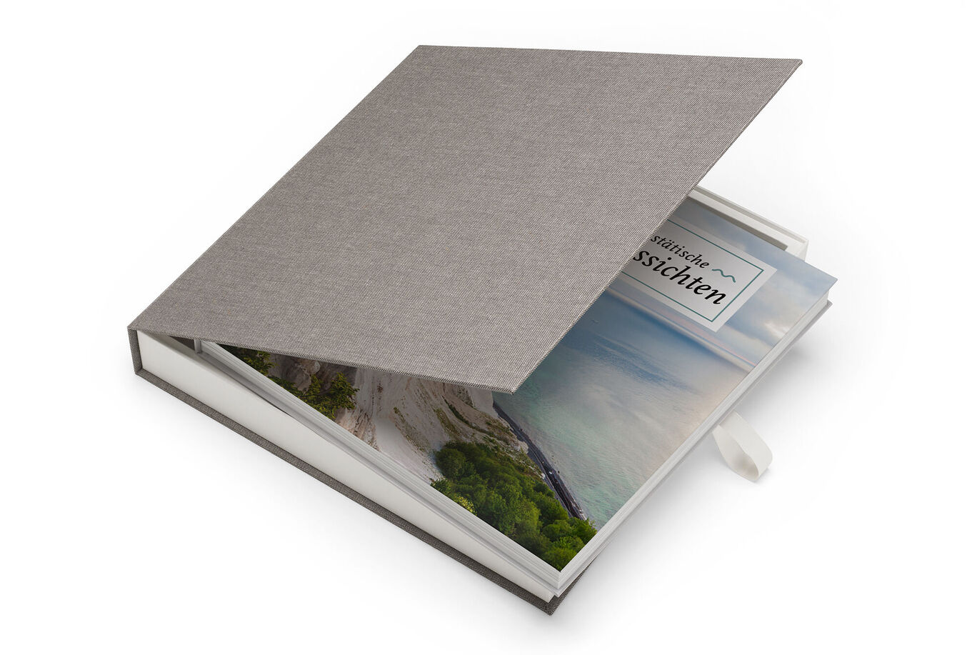 A stylish CEWE PHOTO BOOK with gray fabric cover and window displays a colorful landscape photo.