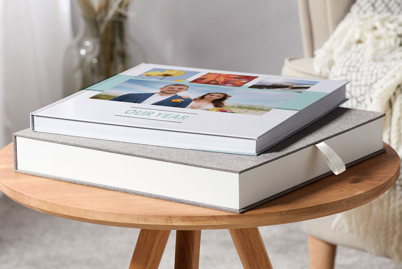 Two CEWE PHOTO BOOKS on a table, one has a cover with photos, the other is plain and decorative.