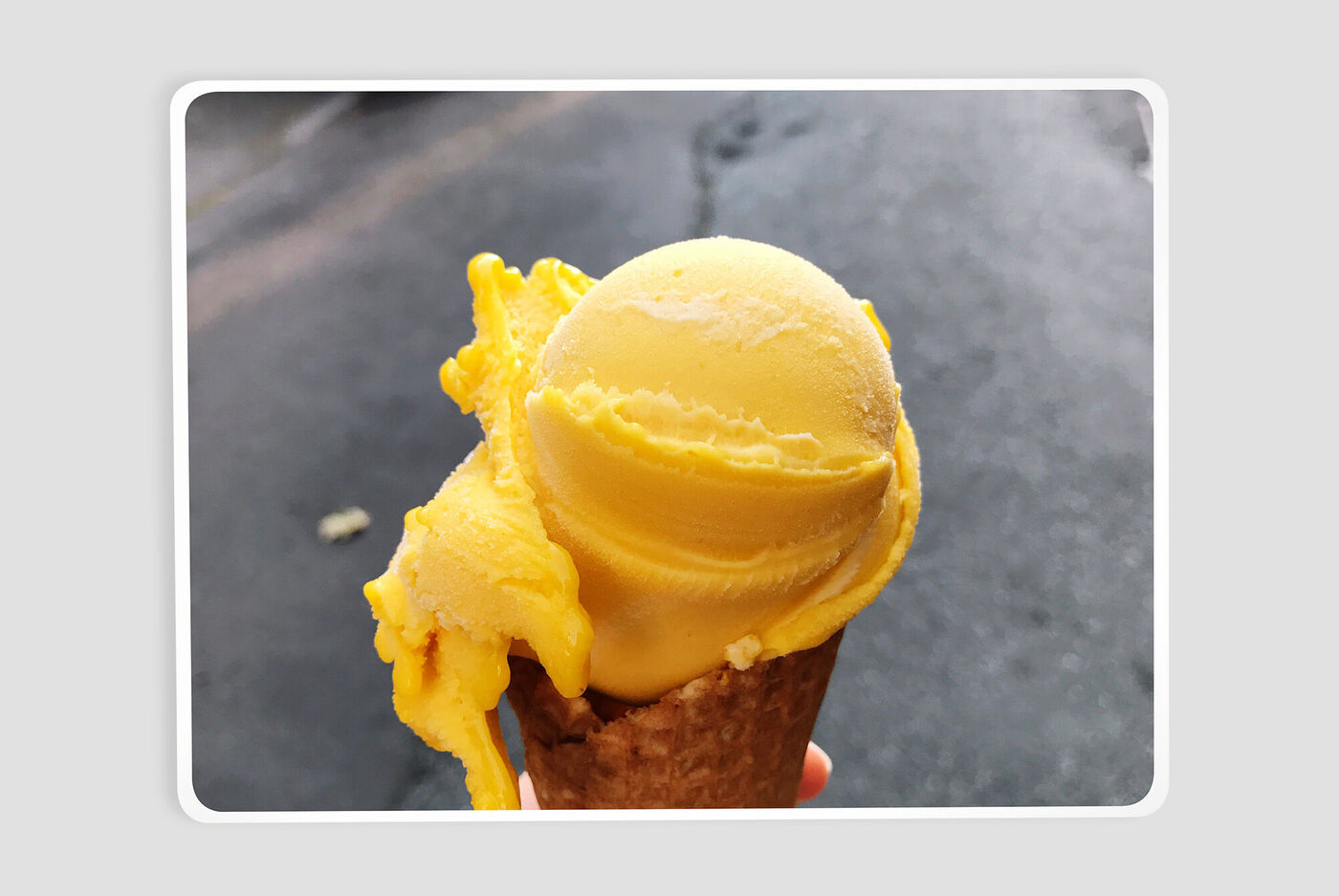 A bright, creamy yellow scoop on a waffle cone. The ice cream looks delicious and refreshing.