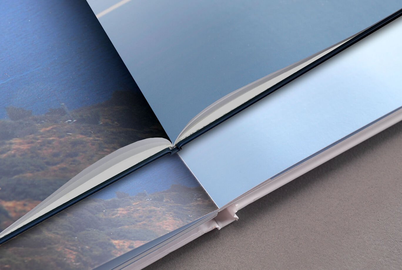 Close-up of an open CEWE PHOTO BOOK with blue pages and a landscape picture.