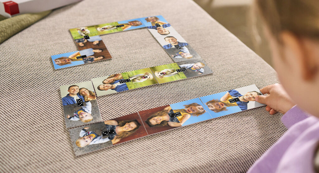 A child plays with a personalized photo puzzle made from images of happy moments. Arranged on a bright sofa.