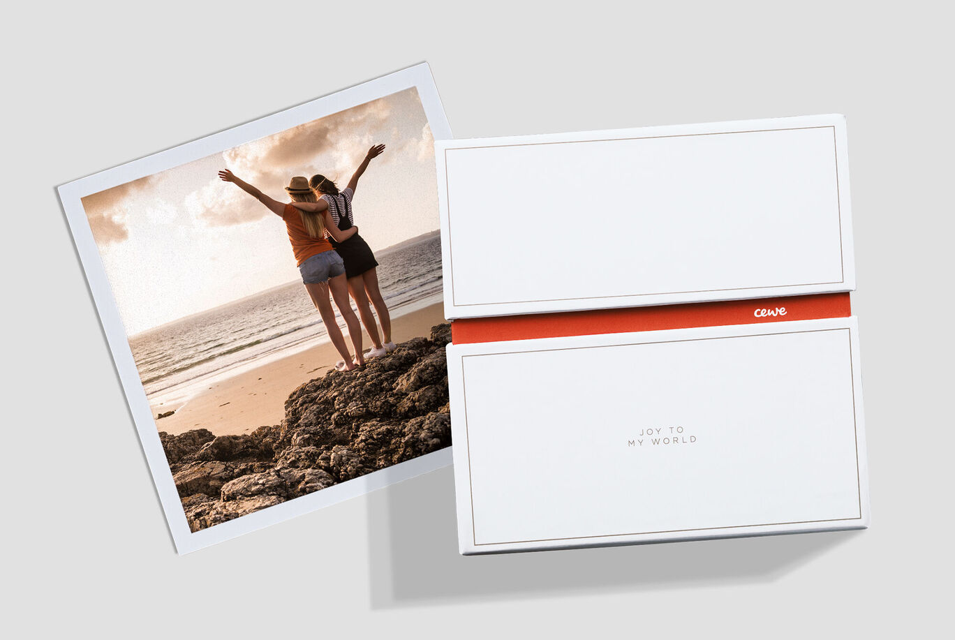 Two friends stand on a rock at the beach, with the sea in the background.