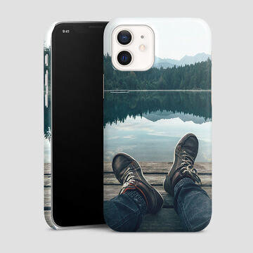A smartphone with a photo case lying on a wooden jetty by a calm lake, surrounded by mountains