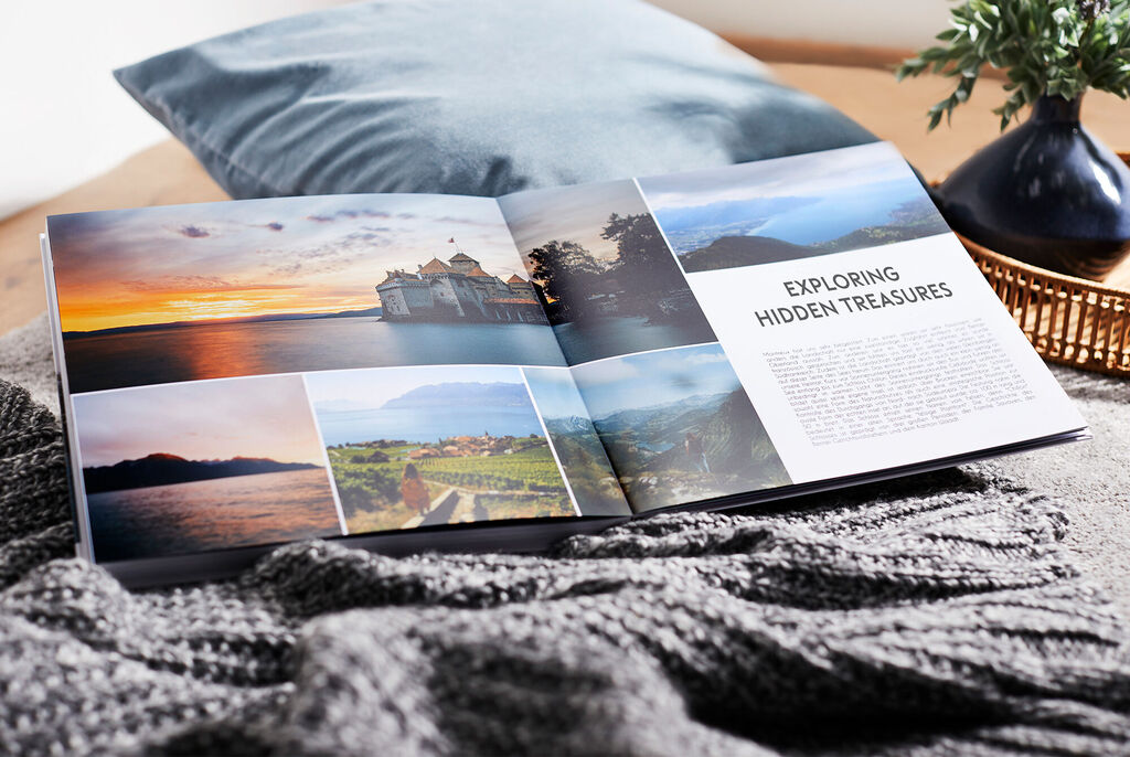 An open photo book lies on a cozy blanket. It shows stunning landscapes and memory moments.