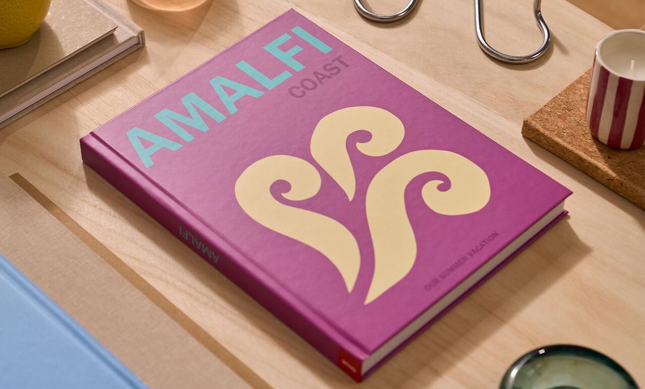 An Amalfi coast-themed coffee table book laying on a wooden table.