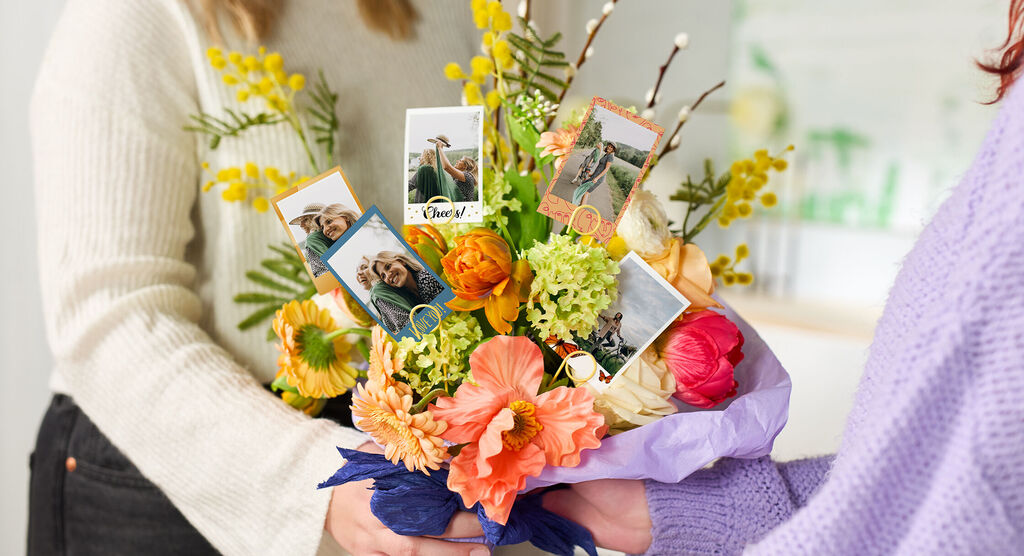Colorful flowers with photos as decorations, held by two people