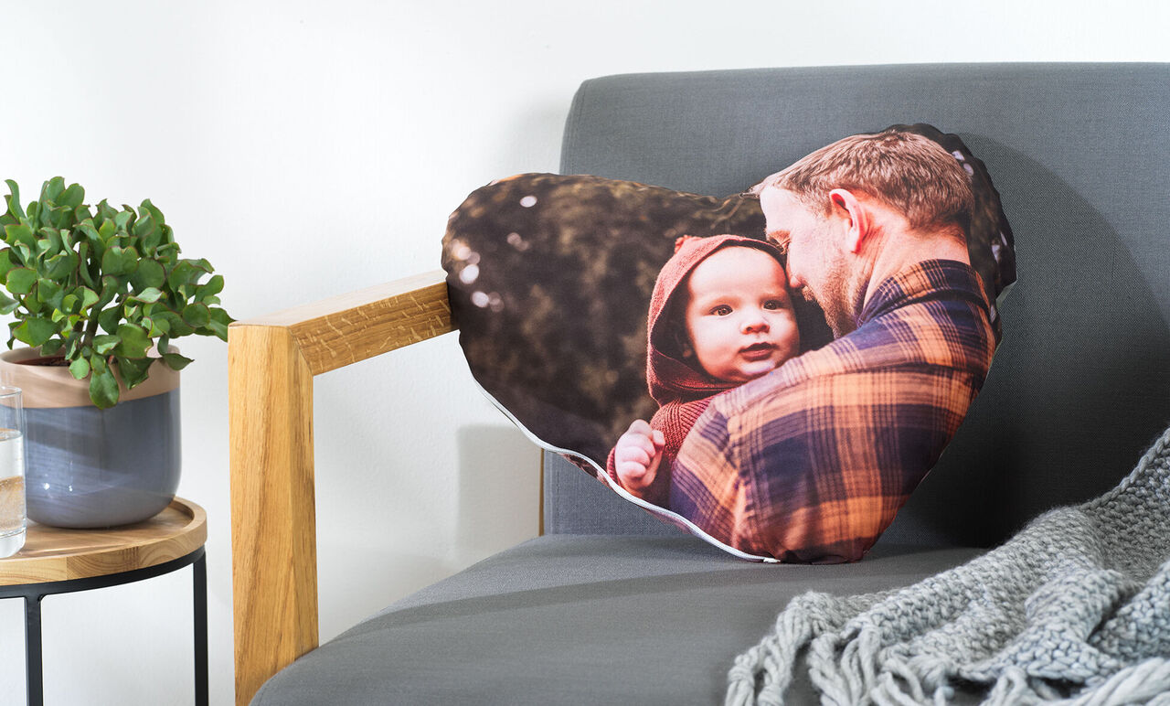 A heart-shaped pillow with a loving photo of a man and a child outdoors.