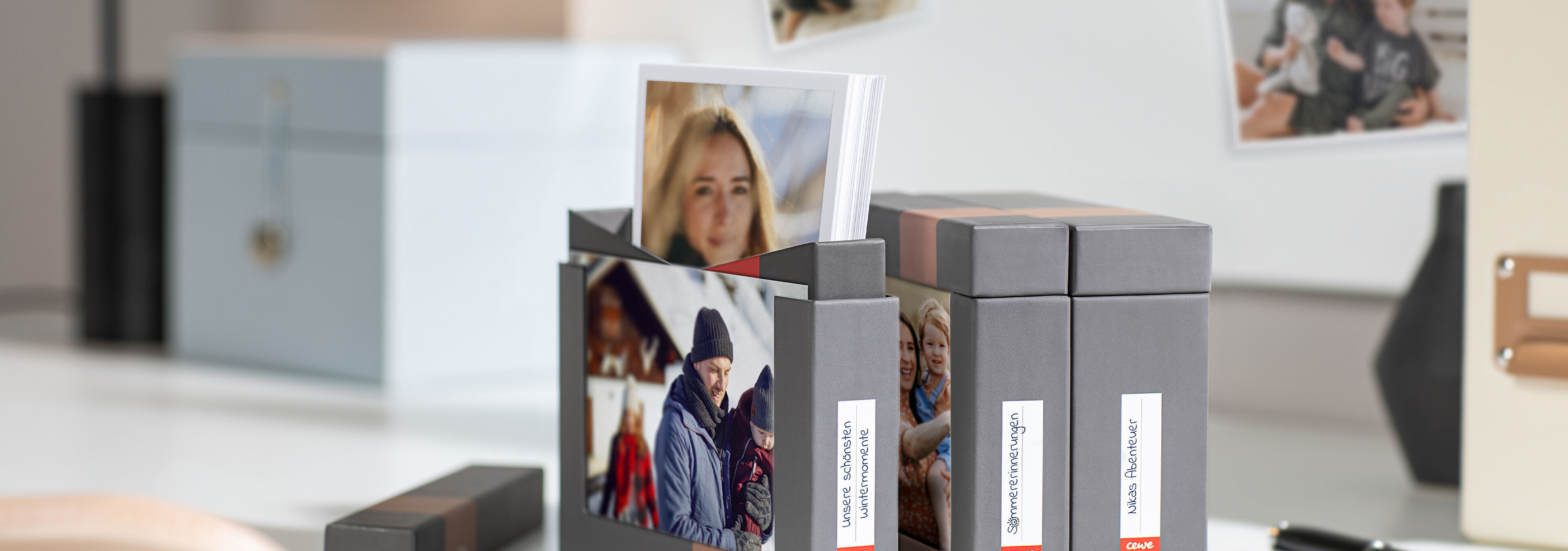 The image shows a stylish box with personal photos. Some pictures are displayed and ready to share. The box sits on an elegant table surrounded by more photographic memories. A creative and loving presentation of memories.
