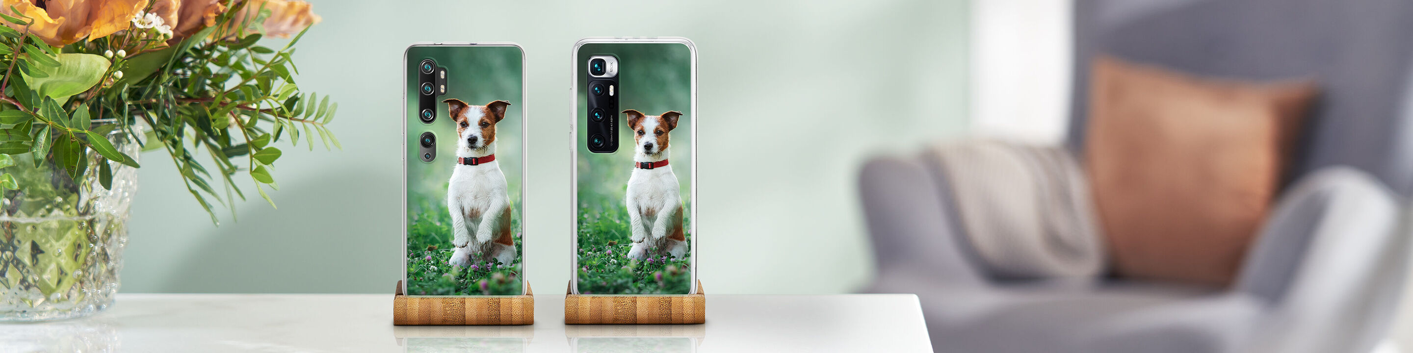 Two smartphones with photos of a dog on a table, surrounded by flowers.
