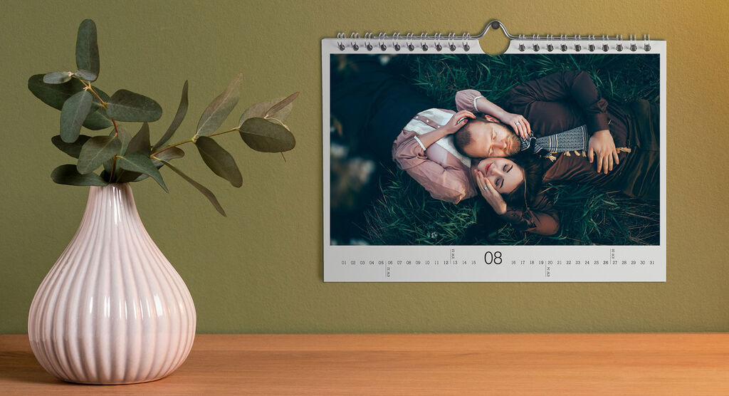 A creative calendar with two people in the grass. The individuals are close and enjoy the moment. Their hug radiates joy.