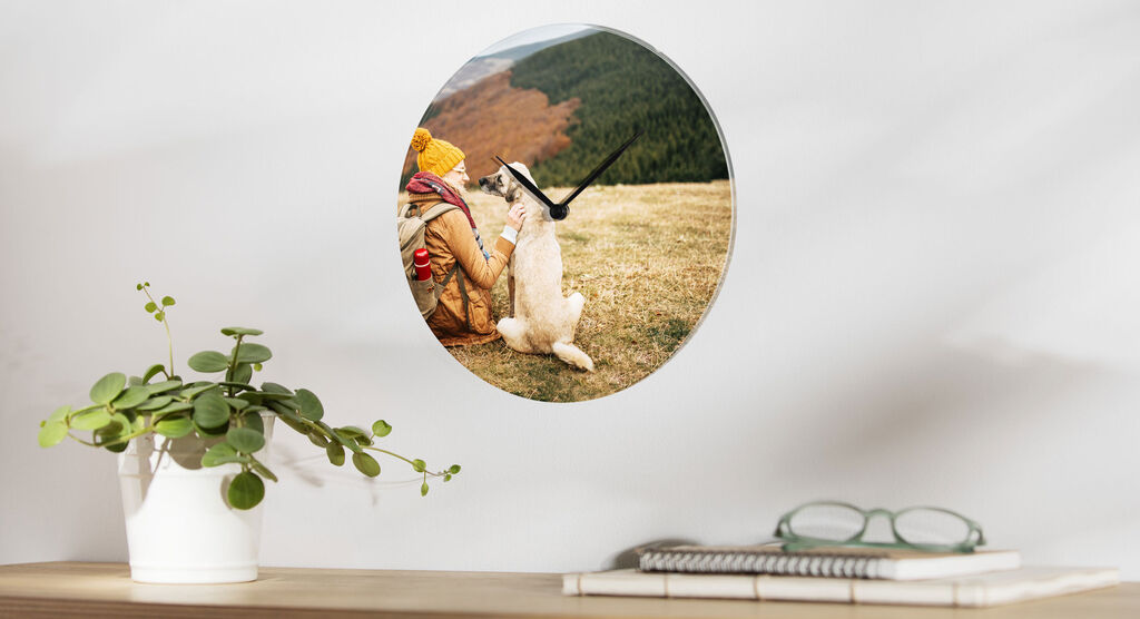 A wall clock featuring a picture of a person and a dog happily outdoors in nature.